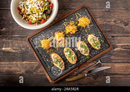 Bruschetta con frutti di mare preparati con sapori asiatici su un tagliere di pietra Foto Stock