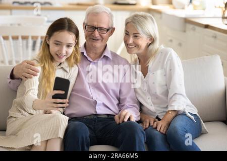 Nonni allegri e bella ragazzina che si fa selfie di famiglia Foto Stock