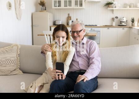 Nonno allegro e ragazza adolescente positiva che fa un ritratto di famiglia Foto Stock