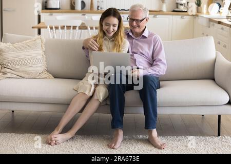 Felice nipotina adolescente e nonno anziano con un portatile Foto Stock