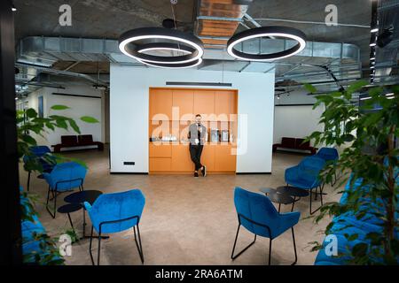 L'uomo si trova nella zona cucina in uno spazio di coworking Foto Stock