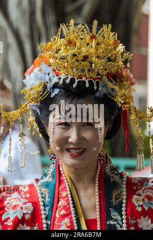 Hong Kong, Cina -- 11 marzo 2023. Ritratto di una donna che indossa un abito da sposa rosso e Gold Crown Foto Stock