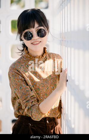 Occhiali da sole rotondi per adolescenti asiatici con abito vintage collezione moda estiva ritratto modello. Foto Stock