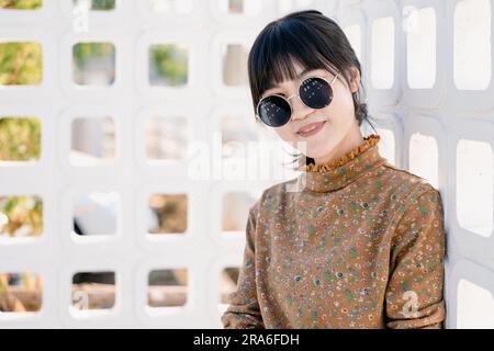 Occhiali da sole rotondi per adolescenti asiatici con abito vintage collezione moda estiva ritratto modello. Foto Stock