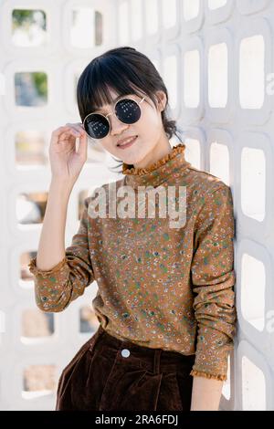 Occhiali da sole rotondi per adolescenti asiatici con abito vintage collezione moda estiva ritratto modello. Foto Stock