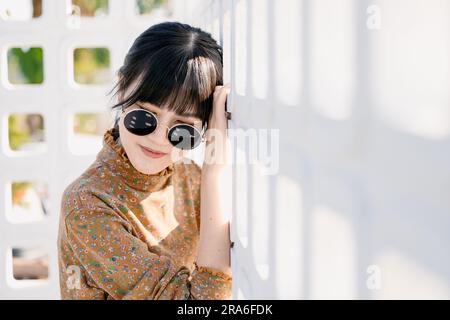 Occhiali da sole rotondi per adolescenti asiatici con abito vintage collezione moda estiva ritratto modello. Foto Stock