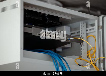 Switch di rete LAN a rack singolo in armadietto per l'installazione del sito di collegamento per la condivisione di Internet con fibra ottica gigabit. Foto Stock