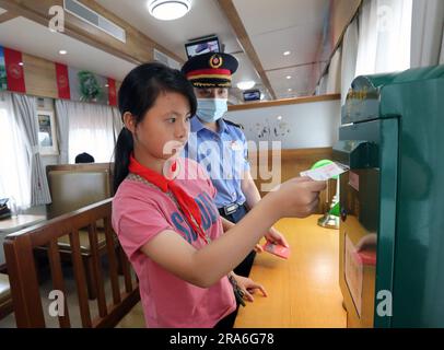 (230701) -- SHANGHAI, 1 luglio 2023 (Xinhua) -- Un giovane passeggero invia una cartolina sul treno n. Y701 che corre tra Shanghai della Cina orientale e Jiaxing della provincia di Zhejiang della Cina orientale, 30 giugno 2023. Il 25 giugno 2021, in occasione del centenario della fondazione del Partito Comunista Cinese, il No Il treno turistico Y701 "Nanhu¤1921" da Shanghai a Jiaxing è stato lanciato per la prima volta, collegando le risorse turistiche di Shanghai e Jiaxing, che sono legate alla storia fondatore e rivoluzionaria del Partito. Il treno ora effettua un viaggio di andata e ritorno una volta al giorno tra Shanghai West Railwa Foto Stock