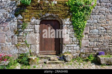 Porta in un muro di pietra nel centro storico del borgo medievale di Locronan in Bretagna con le storiche case in pietra, Francia Foto Stock