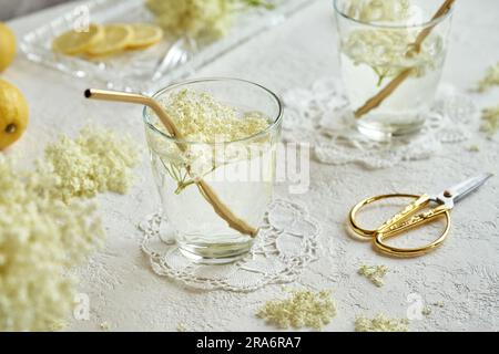 Fiori di sambuco freschi in bicchieri d'acqua con cannucce in metallo dorato. Concetto di zero rifiuti. Foto Stock