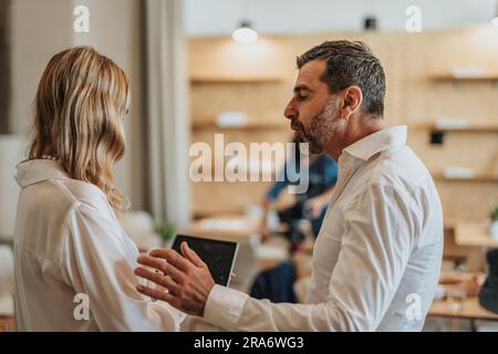 Giovane donna e bell'uomo che indossa magliette bianche mentre parla di lavoro Foto Stock