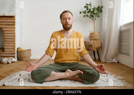 Uomo sportivo e attento a meditare da solo nell'appartamento di casa Foto Stock