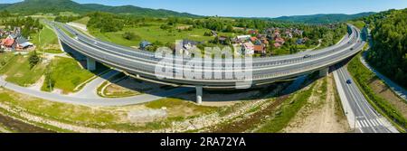 Nuova curva sopraelevata su una vecchia strada Zakopianka nel villaggio di Lubien in Polonia. Ampio panorama aereo Foto Stock