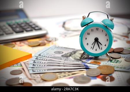 sveglia, denaro e calcolatrice sul tavolo da lavoro Foto Stock