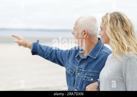 uomo maturo e donna più giovane che camminano per mare Foto Stock