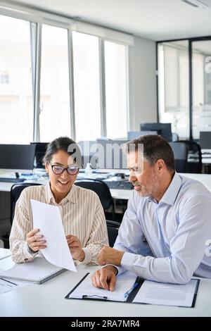 Giovane account manager asiatico che mostra il documento al partner che fornisce il servizio legale. Foto Stock