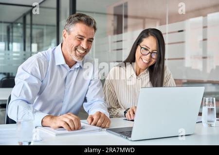 Dirigenti soddisfatti e diversificati team di due manager professionisti che guardano al notebook. Foto Stock