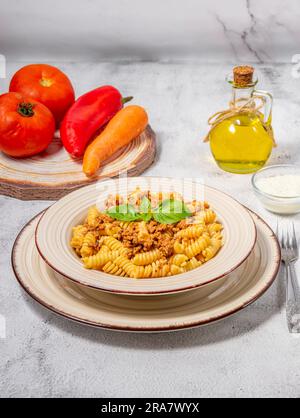 Fusilli con carne macinata, salsa di pomodoro, formaggio e basilico Foto Stock
