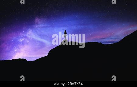 Silhouette di donna in montagna sotto un bel cielo stellato di notte Foto Stock