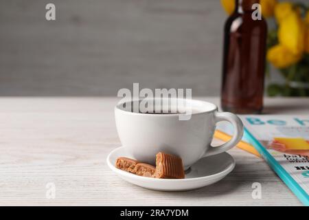 Tazza di caffè aromatico, caramelle al caramello e sciroppo su un tavolo di legno bianco Foto Stock