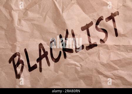 Black Word Blacklist su carta beige stropicciata Foto Stock