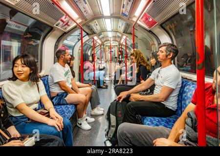 Persone che viaggiano su un treno della Central Line della metropolitana di Londra. Una vista interna all'interno del carrello con i passeggeri seduti. Foto Stock