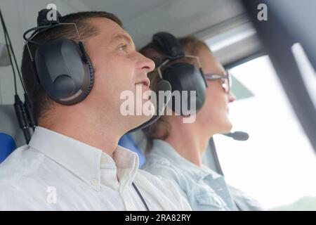 vista ravvicinata dell'uomo e della donna in un aereo che indossa cuffie Foto Stock