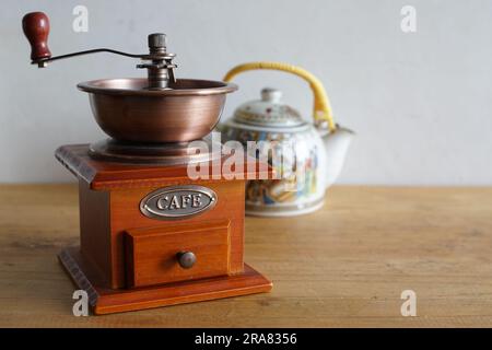 Macinacaffè manuale vintage e tradizionale teiera cinese in ceramica, confronto tra caffè e tè Foto Stock
