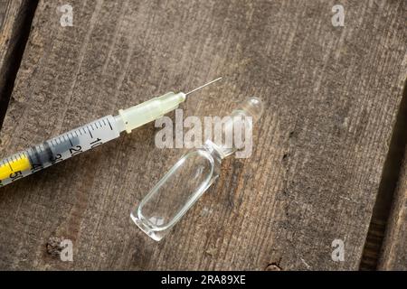 siringa con medicina e fiala giace su uno sfondo di legno da vicino Foto Stock