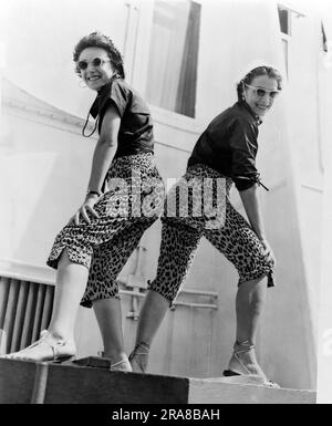 New York, New York: 1953. Due sorelle sfoggiano pantaloni toreador in pelle di leopardo al loro arrivo a bordo della nave Queen Elizabeth a New York. Foto Stock