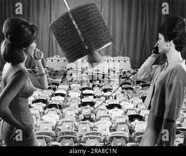 Los Angeles, California: Aprile 1965 i dipendenti della Hughes Aircraft Company utilizzano due dei 480 telefoni che il satellite per comunicazioni Intelsat 1 "Early Bird" può trasmettere in due modi conversazioni telefoniche tra Europa e Nord America. Foto Stock