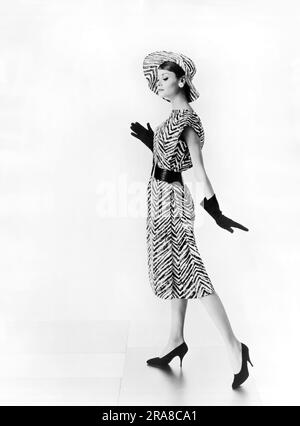 Stati Uniti: c. 1964 Una donna che indossa un abito da giorno stampato in zebra di cotone e un cappello da slouch coordinato disegnato da Estevez Foto Stock