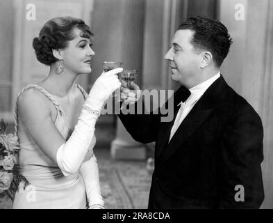 Los Angeles, California: c. 1933 Un uomo e una donna condividono un brindisi in questo film di Hollywood ancora. Foto Stock