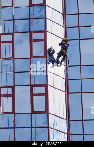 L'addetto alla pulizia delle finestre dell'alto edificio degli uffici stava lavorando diligentemente per assicurarsi che ogni finestra fosse immacolata, anche ai piani superiori. Foto Stock