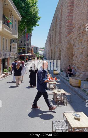 Man serve tè turco in una strada accanto all'Acquedotto di Valente, un Acquedotto romano a Istanbul, Turchia Foto Stock