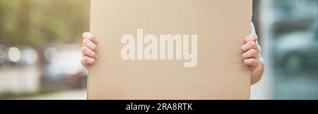 Primo piano di un attivista maschile sorridente che indossa il blu camicia e occhiali che tengono una tavola vuota mentre protestano all'aperto Foto Stock