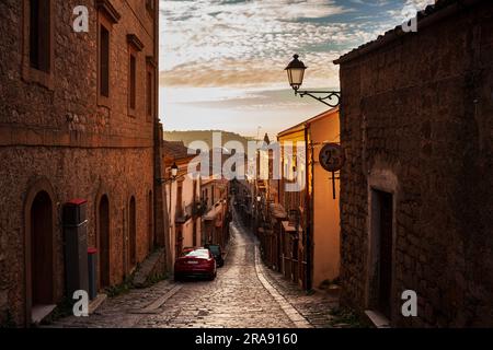 Via con vecchie case di Aidone al tramonto in provincia di Enna, Sicilia in Italia Foto Stock