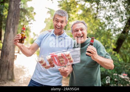 Ritratto di due allegri amici maturi che si divertono al Barbeque Party all'aperto Foto Stock