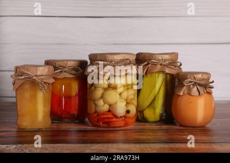 Molti vasetti con diversi ingredienti conservati su un tavolo di legno Foto Stock