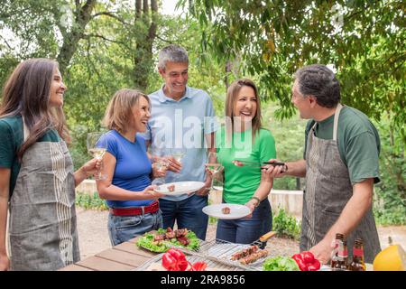 Gruppo di persone mature felici che organizzano una festa barbecue all'aperto Foto Stock