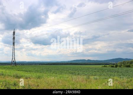 Traliccio elettrico su un campo rurale in campagna. Cielo cupo con nuvole. Foto Stock