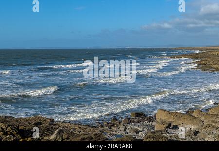 Rest Bay si snoda lateralmente durante una mattinata fresca e ventilata vicino a Porthcawl, sulla costa meridionale del Galles, con onde che vengono sfornate una dopo l'altra. Foto Stock