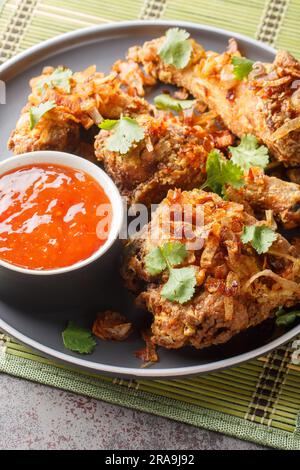 Pollo fritto tailandese in stile Hat Yai con cipolla croccante da vicino su un piatto sul tavolo. Verticale Foto Stock