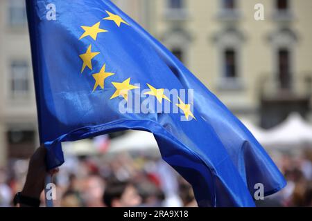 Grande bandiera blu con stelle gialle che simboleggiano l'Unione europea in onde di mani umane durante la manifestazione pubblica a sostegno della democrazia e dell'Unione europea Foto Stock