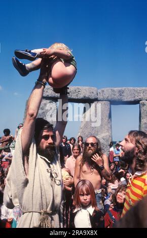 BEV Richardson, conosciuto anche come Pagan Bev, tiene in braccio un giovane ragazzo che è appena stato battezzato per la folla per festeggiare. Stonehenge Free Festival al solstizio d'estate, Wiltshire, Inghilterra 21 giugno 1979. 1970S UK HOMER SYKES Foto Stock