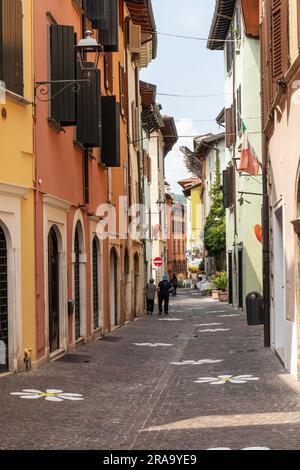 Una pittoresca strada colorata nella città di Salo con fiori dipinti di bianco sulle ciottoli, Salò, Lago di Garda, Italia, Europa Foto Stock