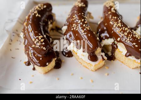 Dessert alla banana con torta di spugna condita con panna montata, banane intere, cioccolato fuso e noci. Foto Stock