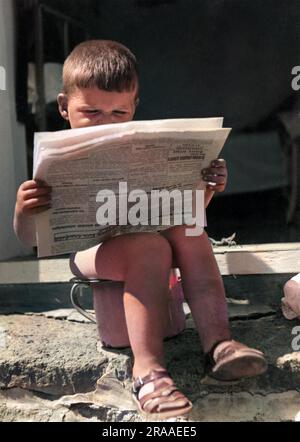 Un bambino legge le ultime notizie mentre è seduto sul vasino! Data: Anni '1930 Foto Stock