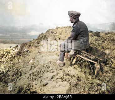 Un soldato britannico seduto su uno sgabello su una collina fangosa sul fronte occidentale durante la prima guerra mondiale, a guardare in lontananza. Data: Circa 1916 Foto Stock