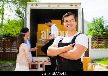 Ritratto sorridente dell'addetto alla consegna presso la sede dei clienti, dei clienti che ricevono la scatola dal corriere, degli addetti alla consegna soddisfatti che controllano l'ordine e lavorano con loro Foto Stock